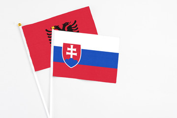 Slovakia and Albania stick flags on white background. High quality fabric, miniature national flag. Peaceful global concept.White floor for copy space.