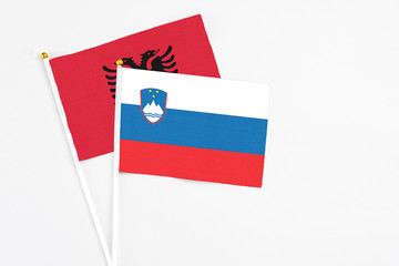 Slovenia and Albania stick flags on white background. High quality fabric, miniature national flag. Peaceful global concept.White floor for copy space.