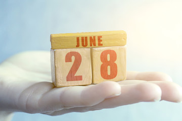 june 28th. Day 28 of month,Handmade wood cube with date month and day on female palm summer month, day of the year concept