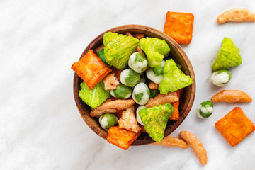 Japanese hot snacks with peas and wasabi lie in a brown bowl and on a white marble surface