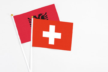 Obraz premium Switzerland and Albania stick flags on white background. High quality fabric, miniature national flag. Peaceful global concept.White floor for copy space.