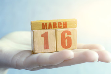 march 16th. Day 16 of month,Handmade wood cube with date month and day on female palm spring month, day of the year concept