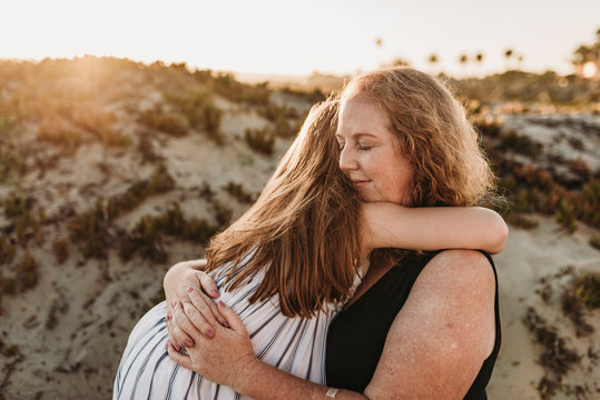 Side view of mother and redheaded elementary age daughter at sunset