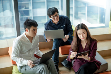 Business meeting and teamwork concept. Asian businesswoman explaining project data report to colleagues using digital tablet for presentation at workplace. Coworkers team brainstorming ideas in office