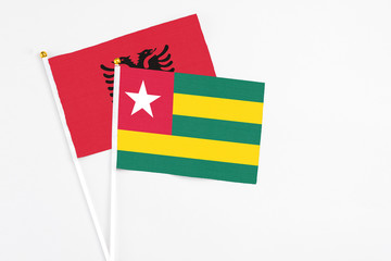 Togo and Albania stick flags on white background. High quality fabric, miniature national flag. Peaceful global concept.White floor for copy space.