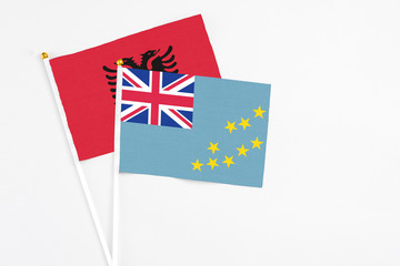 Fototapeta premium Tuvalu and Albania stick flags on white background. High quality fabric, miniature national flag. Peaceful global concept.White floor for copy space.