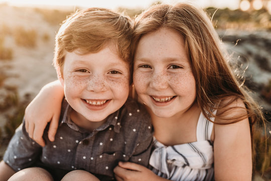 Portrait of young redheaded freckled siblings smiling during sunset
