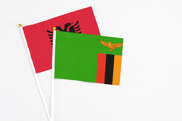 Zambia and Albania stick flags on white background. High quality fabric, miniature national flag. Peaceful global concept.White floor for copy space.