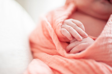 Close up of newborn baby girls hands wrapped in pink blanket
