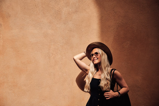 Glamorous female standing by orange wall