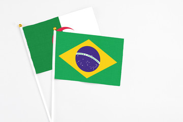 Brazil and Algeria stick flags on white background. High quality fabric, miniature national flag. Peaceful global concept.White floor for copy space.