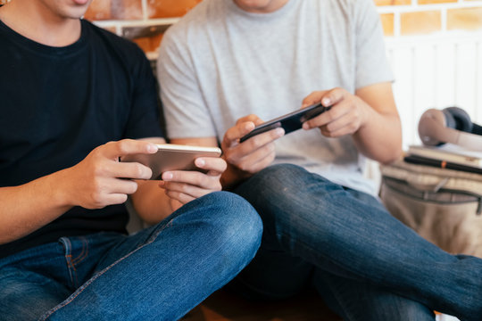 Young teenage men playing mobile game together.