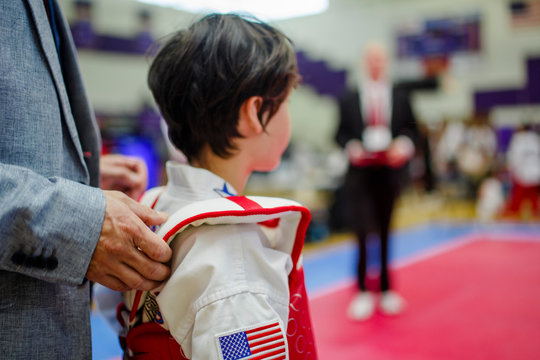 A small boy stands at the edge of a martial arts ring waiting to spar