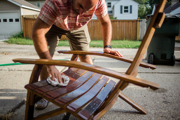 A craftsman polishes a handmade wooden chair outside