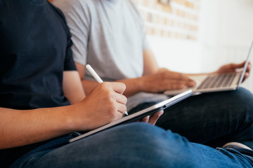 Young teenage men using computer and tablet for online learning.