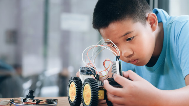 Concentrated boy creating robot at lab.