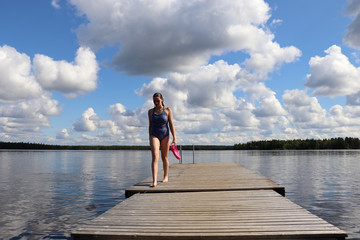 Fototapeta na wymiar Girl walking on dock at Lake Ranuanjarvi in Finland
