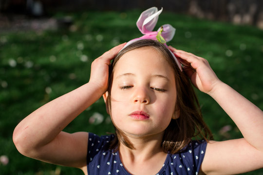 A beautiful little girl with serious expression wears flower for a hat