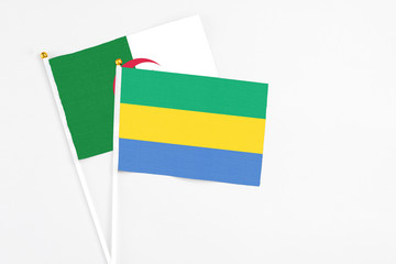 Gabon and Algeria stick flags on white background. High quality fabric, miniature national flag. Peaceful global concept.White floor for copy space.