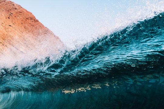Close up of a powerful turquoise wave breaking against blue sky