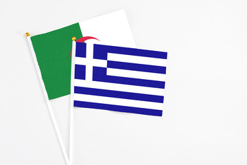Greece and Algeria stick flags on white background. High quality fabric, miniature national flag. Peaceful global concept.White floor for copy space.