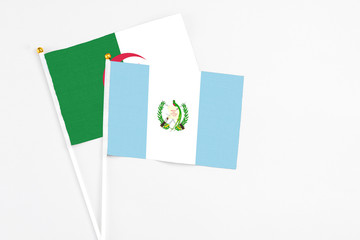 Guatemala and Algeria stick flags on white background. High quality fabric, miniature national flag. Peaceful global concept.White floor for copy space.