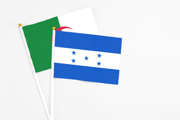 Honduras and Algeria stick flags on white background. High quality fabric, miniature national flag. Peaceful global concept.White floor for copy space.