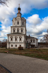 Fototapeta na wymiar An ancient Orthodox church on the territory of the Andrei Rublev Museum in Moscow against a cloudy sky. In the foreground is a gravel path