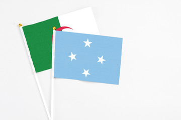 Micronesia and Algeria stick flags on white background. High quality fabric, miniature national flag. Peaceful global concept.White floor for copy space.