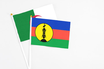New Caledonia and Algeria stick flags on white background. High quality fabric, miniature national flag. Peaceful global concept.White floor for copy space.