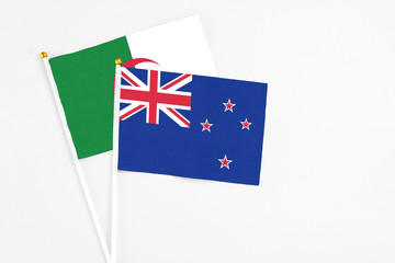 New Zealand and Algeria stick flags on white background. High quality fabric, miniature national flag. Peaceful global concept.White floor for copy space.