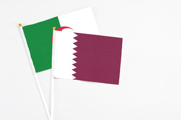 Qatar and Algeria stick flags on white background. High quality fabric, miniature national flag. Peaceful global concept.White floor for copy space.