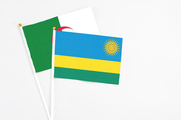 Rwanda and Algeria stick flags on white background. High quality fabric, miniature national flag. Peaceful global concept.White floor for copy space.