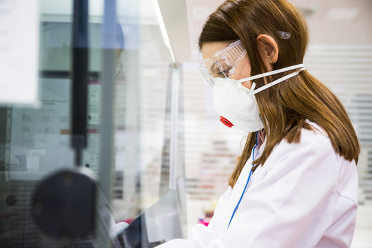 Young woman wearing safety mask and goggles while working in a laboratory