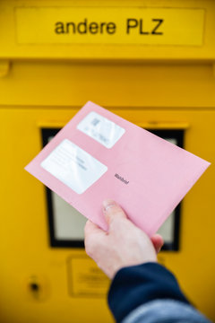 Elector holding documtents for the postal vote in front of the mailbox