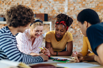 Young people sitting together at table and talking