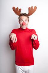 Young man wearing red nose and reindeer antlers holding his hoofs up for a funny holiday party portrait