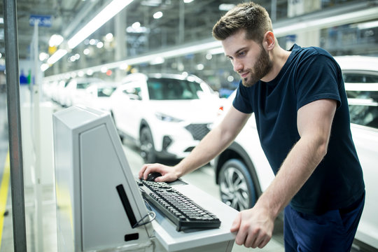 Man working on computer in modern car factory