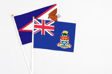 Fototapeta premium Cayman Islands and American Samoa stick flags on white background. High quality fabric, miniature national flag. Peaceful global concept.White floor for copy space.