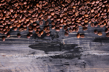 Roasted brown coffee beans scattered on wood textured table with a lot copy space for text. Flat lay composition. Close up, top view, background.