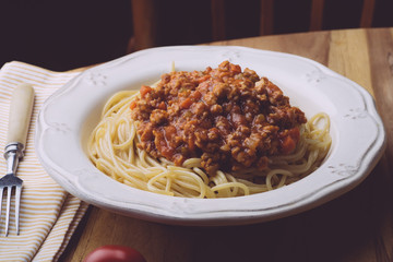 Pasta bolognese (spaghetti bolognese) and parmesan on a white plate. The classic italian spaghetti on old wooden background
