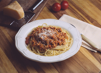 Pasta bolognese (spaghetti bolognese) and parmesan on a white plate. The classic italian spaghetti on old wooden background