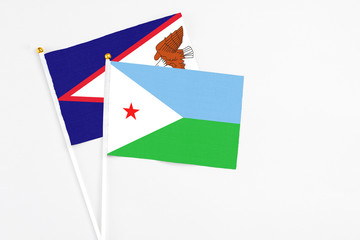 Djibouti and American Samoa stick flags on white background. High quality fabric, miniature national flag. Peaceful global concept.White floor for copy space.