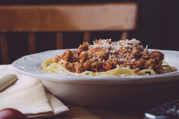 Pasta bolognese (spaghetti bolognese) and parmesan on a white plate. The classic italian spaghetti on old wooden background