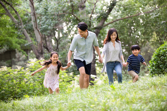 Happy young Chinese family running on grass