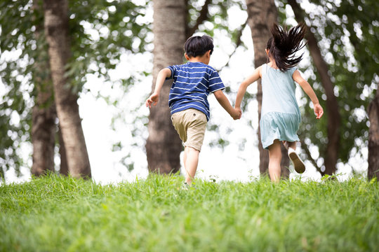 Two Chinese children running on grass