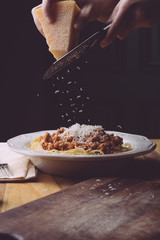 Pasta bolognese (spaghetti bolognese) and parmesan on a white plate. The classic italian spaghetti on old wooden background