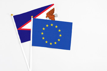 European Union and American Samoa stick flags on white background. High quality fabric, miniature national flag. Peaceful global concept.White floor for copy space.