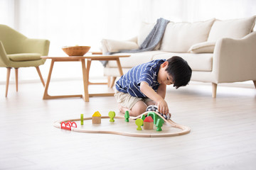 Little Chinese boy playing with toy train on floor