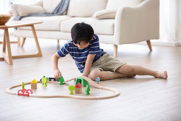 Little Chinese boy playing with toy train on floor